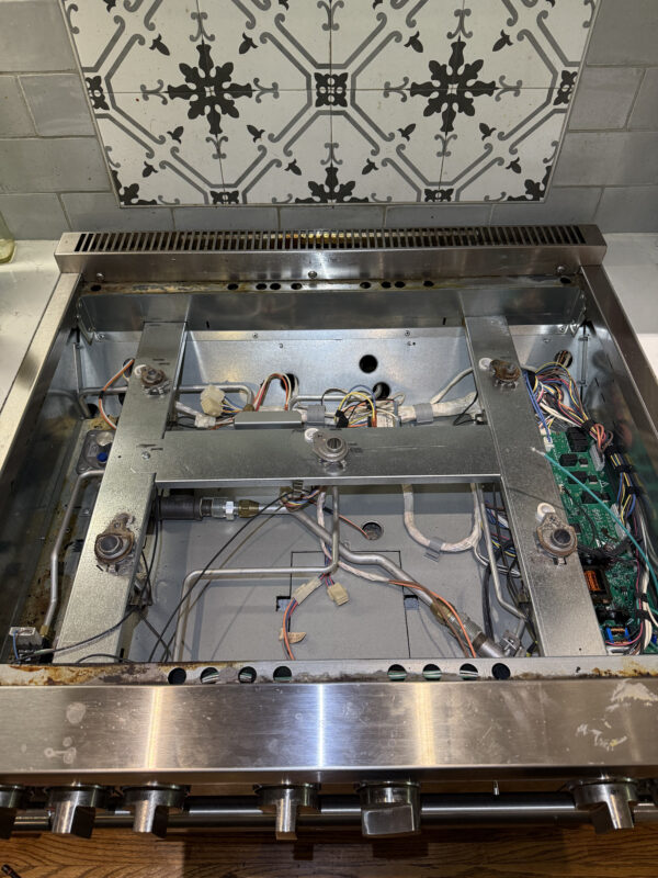 The Thermador range is disassembled. The burners and cover need to be removed to access the control board.