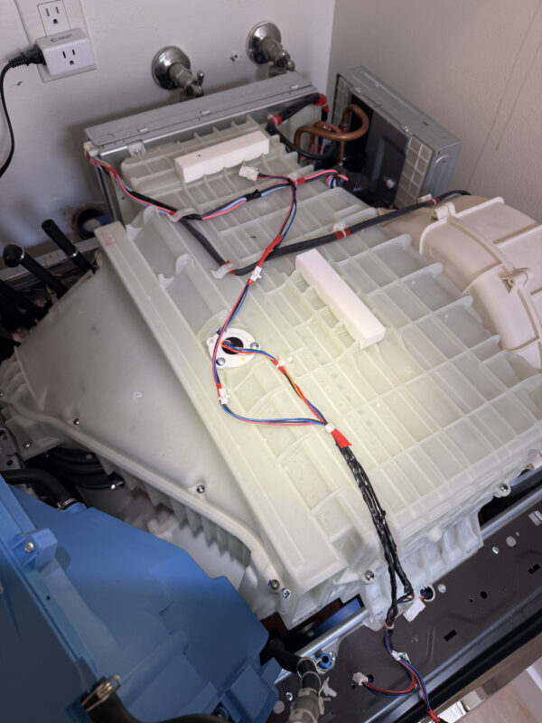 The dispenser must be removed to access the filter and coils—it's a bit tricky. Disconnect the hoses and remove the screws.